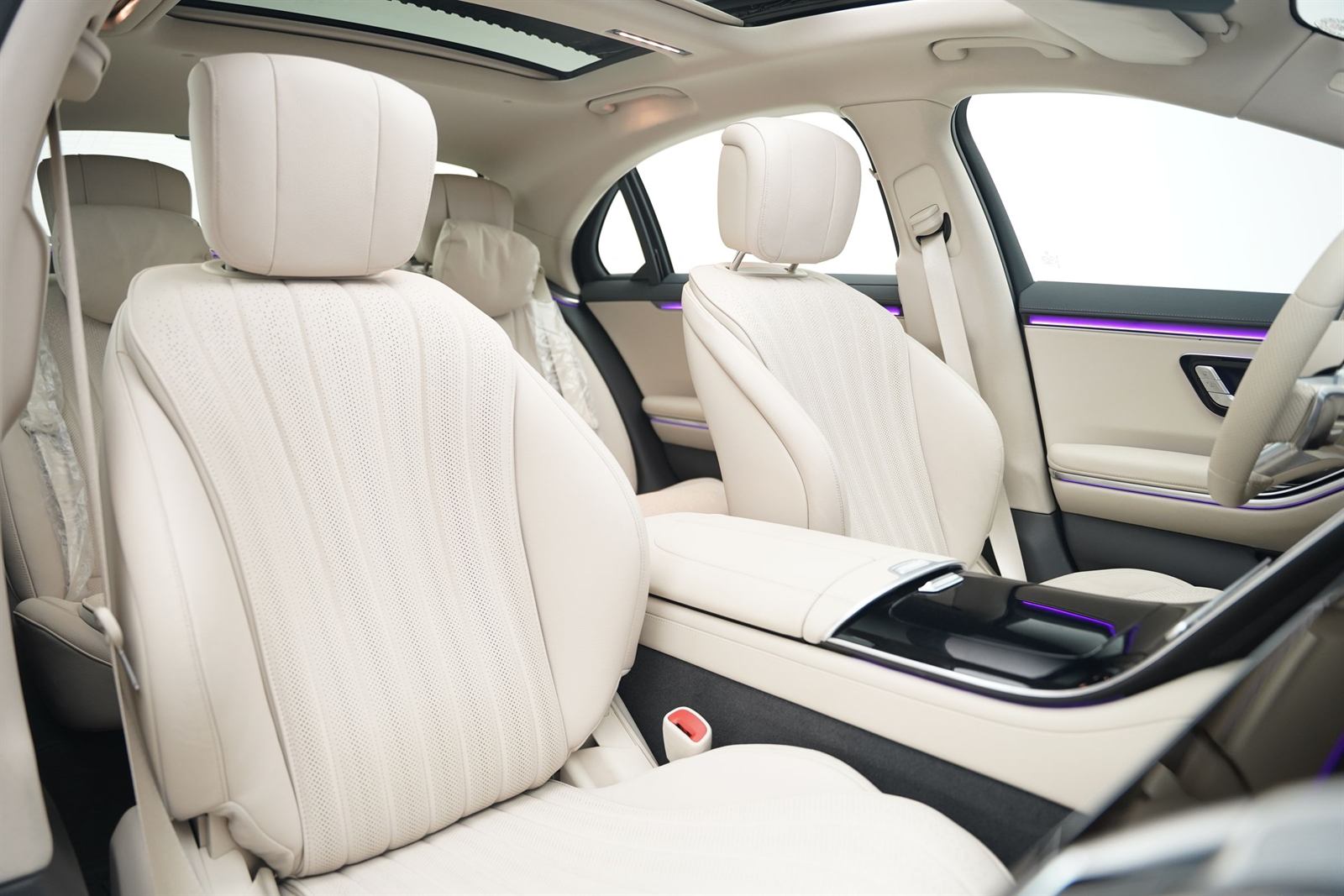 The cabin of a large sedan, light leather seats and glass roof